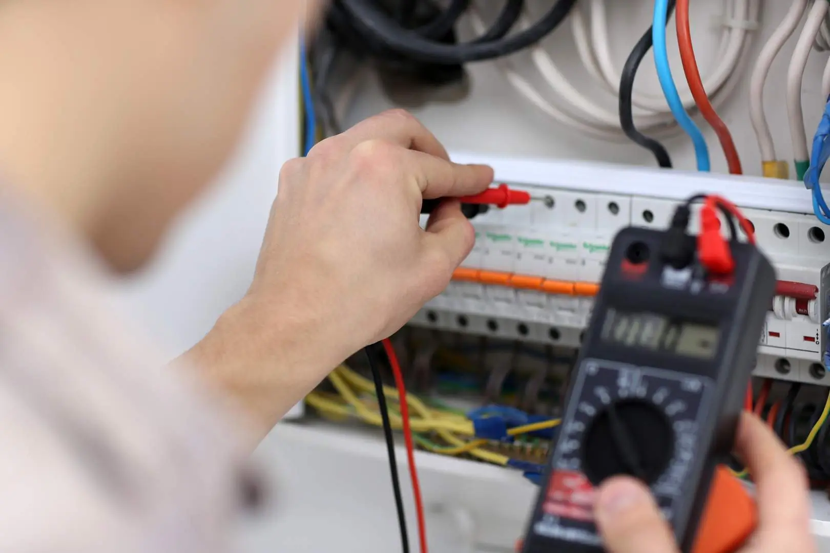 Electrician – Blacktown – technician using a multimeter to test wiring inside a household switchboard.