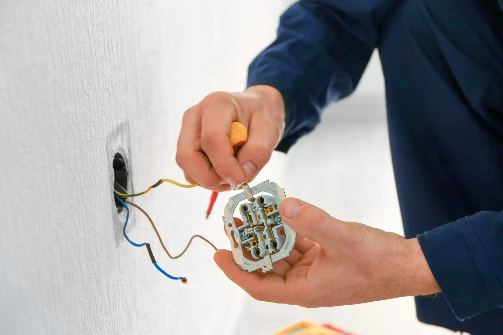 Electrician – North Sydney – worker installing new wall socket wiring during residential electrical maintenance.