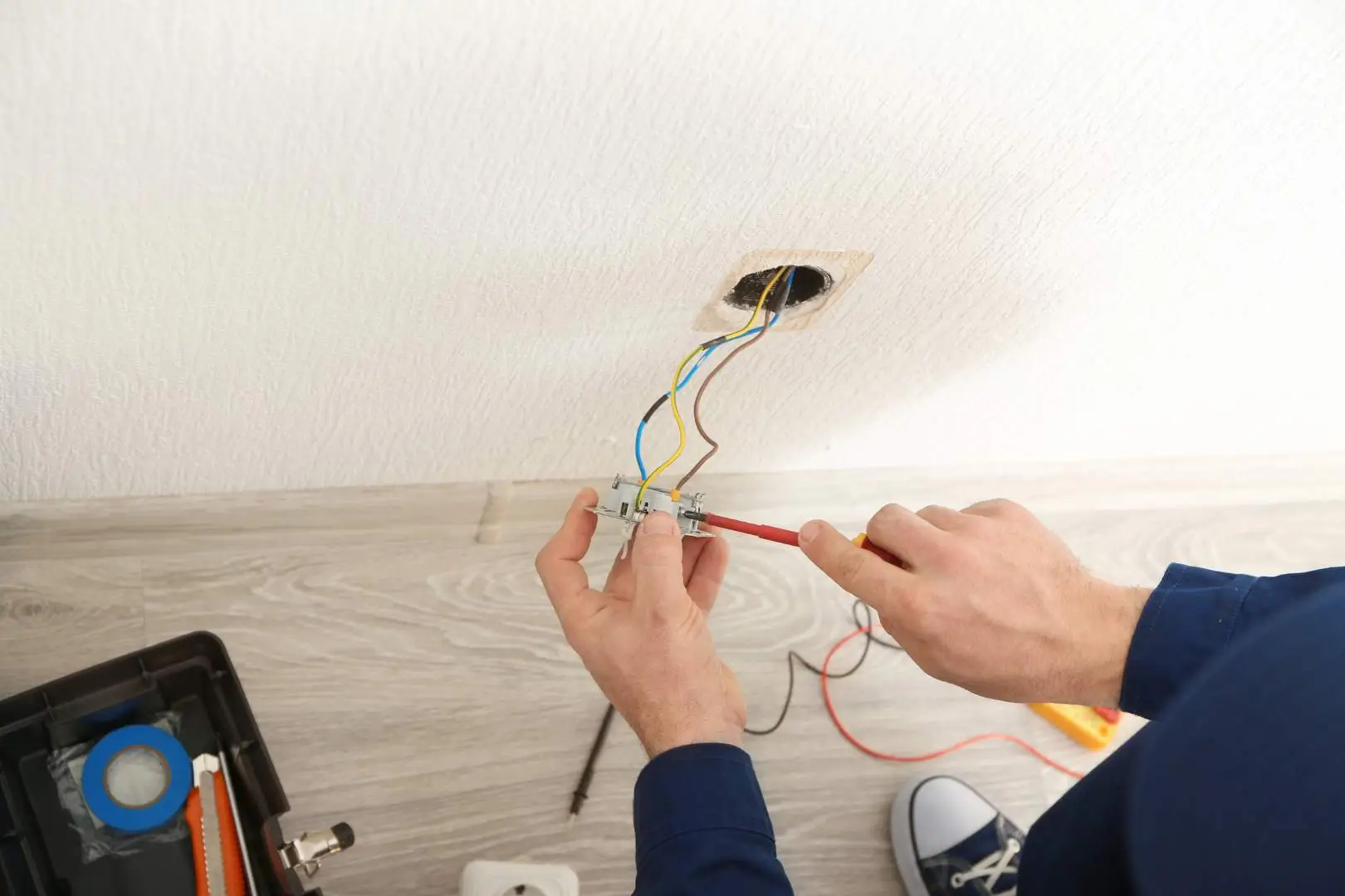 Electrician – Sydney CBD – tradesperson connecting wall wiring to a power outlet during electrical installation.
