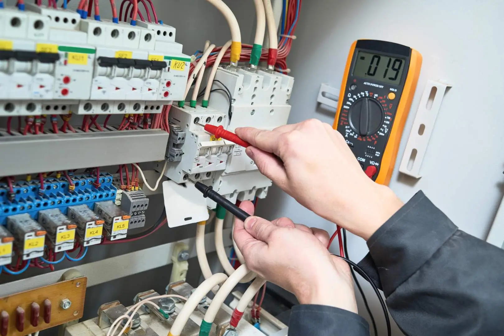 Electrician – Blacktown – technician testing voltage on a commercial switchboard with a digital multimeter.