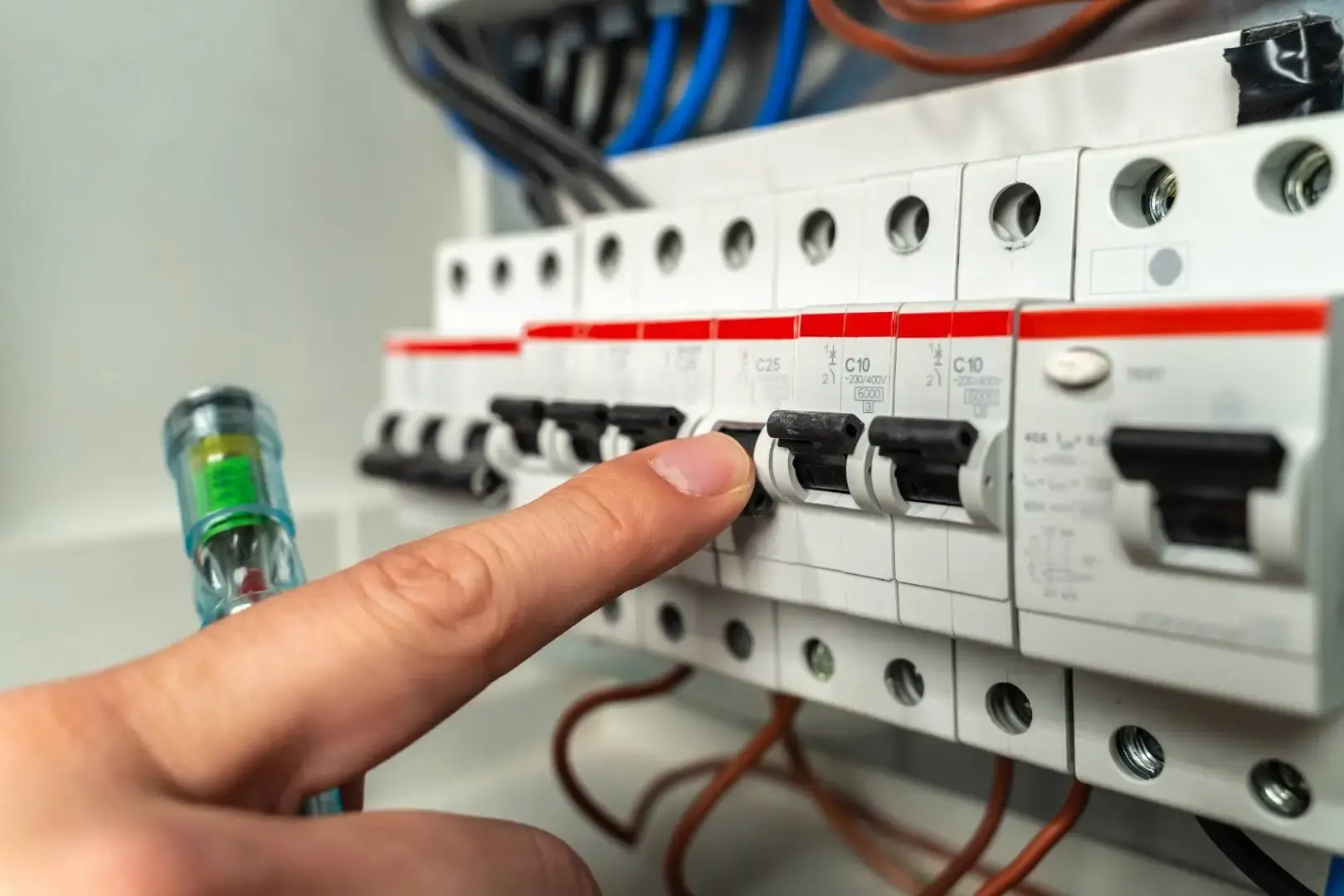 Close-up of an electrician resetting a circuit breaker inside a modern electrical distribution board.