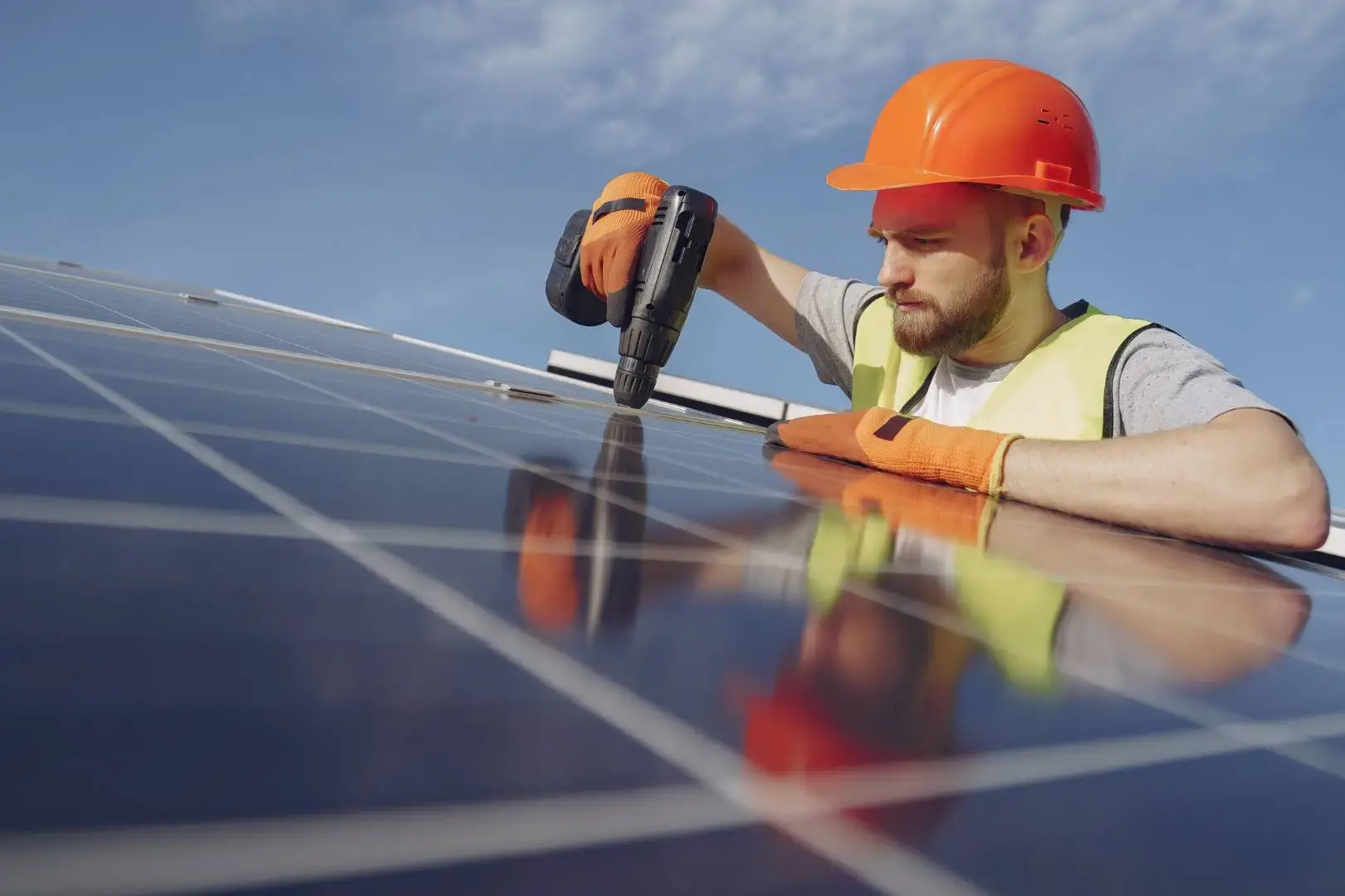 Electrician installing and securing electrical wiring inside a wall cavity, with junction boxes and cables visible.